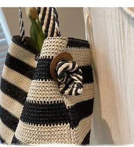Detail of striped straw beach tote with metal eyelets and decorative rope knot accent