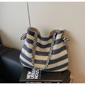 Detail view of woven striped tote bag featuring decorative oversized knots on the sides