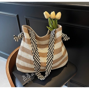 Detail of striped woven tote bag with printed shoulder strap and side decorative knots
