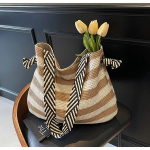 Detail of striped straw beach tote with thick woven shoulder strap and side knot accents