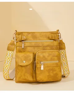 Macro shot of yellow faux leather crossbody bag with jacquard strap and gold hardware