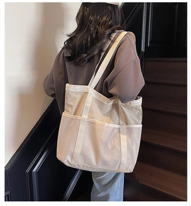 Detalle del bolso tote de lona beige con bolsillos de malla y correa de hombro tejida
