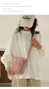 Detailed close-up of a pink canvas crossbody bag with multiple zipper compartments