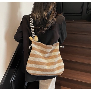 Close-up of a striped woven beach tote with patterned shoulder straps on a wooden staircase