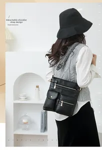 Detail view of black textured PU leather bag with wide jacquard strap and zip pockets