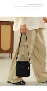 Detail view of the black canvas crossbody bag featuring adjustable strap and front pocket
