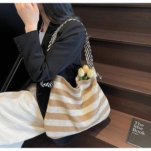 Straw beach bag detail showing striped weave and decorative black and white shoulder strap