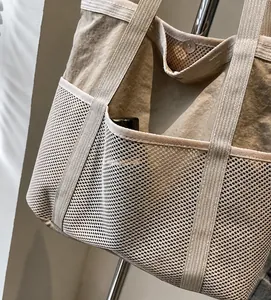 Detail van beige nylon draagtas met zijvakken van gaas en metalen drukknoopsluiting