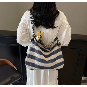 Detail of blue and white striped straw beach bag with thick knotted shoulder strap