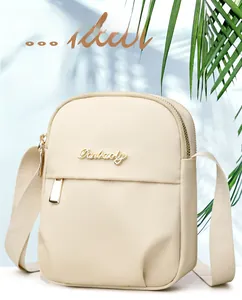 Detail of a cream nylon mobile phone bag with golden metal logo and premium zipper