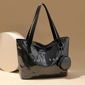 Large black glossy PVC tote bag with white TOTE BAG text and matching small round pouch