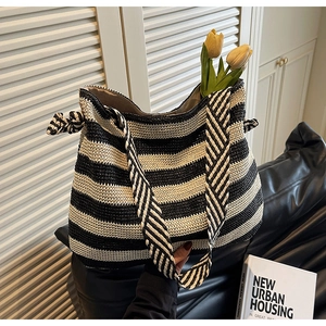 Detail of handwoven black and white striped straw tote with a wide decorative strap