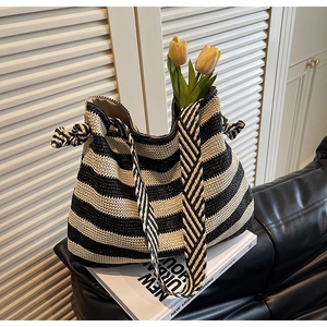 Detail of black and white striped straw beach bag on a leather sofa with a magazine