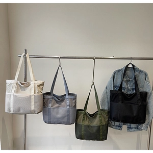 Detalle de bolsos tote de lona y malla en cuatro colores colgados para almacenaje