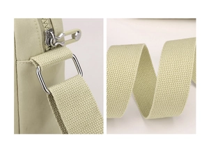 Close-up of durable canvas strap and smooth metal zipper on light green crossbody bag