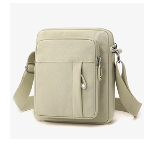 Detail of sage green nylon crossbody bag showing zippered pocket and printed lettering