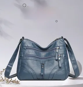 Detailed view of deep blue textured PU leather crossbody bag with multiple zip pockets
