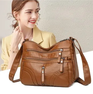 Detail of a brown multi-zippered soft PU leather crossbody bag worn by a model