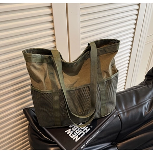 Detalle del bolso tote de lona verde militar con bolsillos de malla y cierre a presión