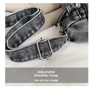 Détail de la bandoulière réglable avec boucle en métal sur un sac en denim gris foncé