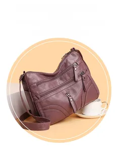 Detail of dark purple litchi grain leather crossbody bag with three zipper pockets
