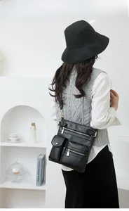 Close-up of black PU leather crossbody bag with multiple pockets and gold zippers