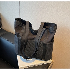 Detalle de bolso tote de nailon negro con paneles de malla sobre fondo de cuero