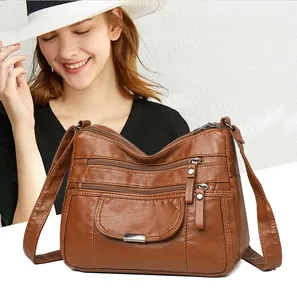 Detail view of caramel brown washed faux leather crossbody bag with multiple zip pockets