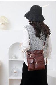 Detail of dark brown vintage leather crossbody bag featuring multiple functional pockets