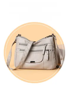 Close-up of the washed soft leather texture and zipper pockets on the beige crossbody bag