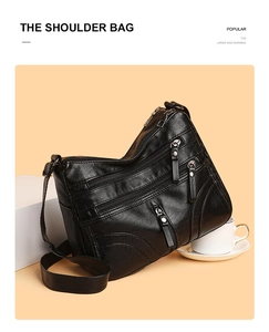 Detail of black faux leather shoulder bag with multiple zippers and adjustable strap