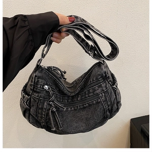 Détail du sac bandoulière en denim gris avec fermetures éclair et plis texturés