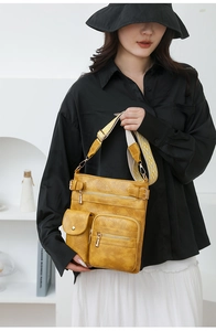 Detail view of yellow PU leather crossbody bag with multiple pockets and patterned wide strap
