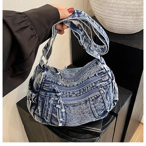 Détail du sac bandoulière en denim bleu vintage avec trois poches zippées et bandoulière