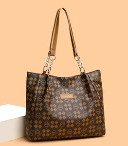Détail d'un cabas vintage marron avec motif logo et poignée en chaîne et cuir souple