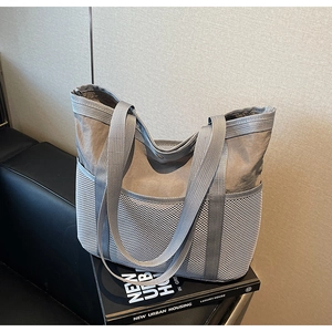 Primer plano del bolso tote de nailon gris con práctico bolsillo lateral de malla