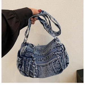 Détail du sac fourre-tout en denim bleu vintage avec poches zippées et texture délavée
