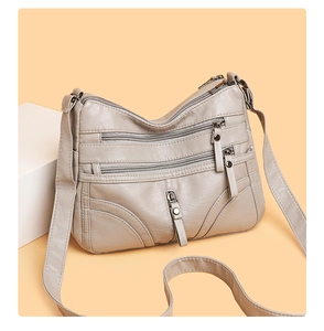 Detail view of a soft grey PU leather crossbody bag featuring multiple zipper pockets