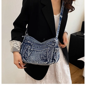 Détail d'un sac hobo en denim bleu délavé avec plusieurs fermetures éclair pratiques