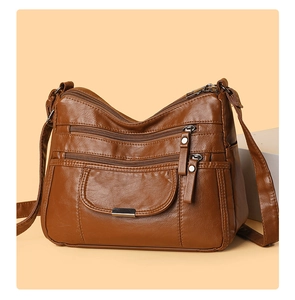 Close-up of soft brown leather crossbody bag with multiple zipper compartments and adjustable strap