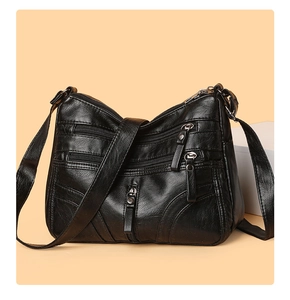 Detail view of black soft leather crossbody bag featuring multiple zipper pockets