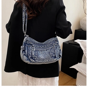 Vue détaillée du sac bandoulière en denim délavé avec plusieurs poches zippées pratiques