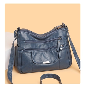 Detail of blue multi-zipper crossbody bag with soft lychee grain leather texture
