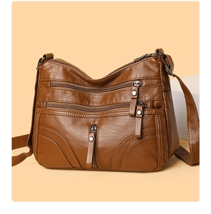Detail of dark brown faux leather crossbody bag showing three front zipper compartments