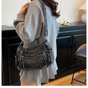 Détail du sac fourre-tout en denim délavé avec poches zippées et cordons de serrage latéraux