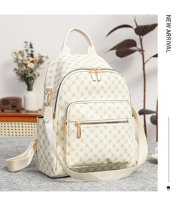 Dettaglio dello zaino beige con motivo a quadrifoglio e finiture in metallo dorato