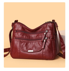 Detail view of burgundy soft leather crossbody bag featuring multiple zipper pockets