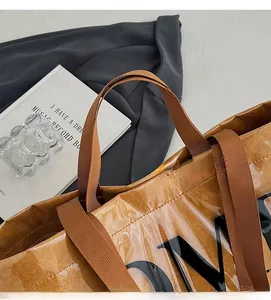 Detailed close-up of brown glossy tote bag with black letters and nylon handles