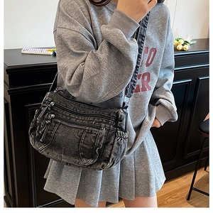 Détail du sac cabas en jean noir avec plusieurs poches zippées et bandoulière large