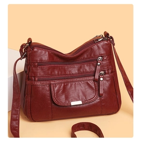 Close-up of burgundy soft faux leather crossbody bag with multiple zipper pockets